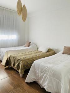 2 camas en un dormitorio con paredes blancas y suelo de madera en Garden 33 1A en Chivilcoy