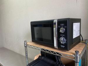 福井市にあるAz Inn Fukui - Vacation STAY 65940vの木製の棚に座る黒い電子レンジ