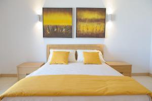 um quarto com uma cama com lençóis amarelos e dois quadros em Agua Hotels Sal Vila Verde em Santa Maria