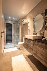 La salle de bains est pourvue d'un lavabo, de toilettes et d'un miroir. dans l'établissement Hidden Villas by Matira Beach, à Bora Bora