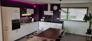 a kitchen with white cabinets and a wooden table at Rodez Aveyron appart. T4 neuf 2 places parking in Rodez