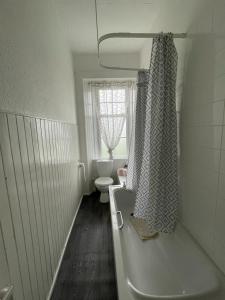 baño con bañera, aseo y ventana en Our Wee Getaway, en Rothesay