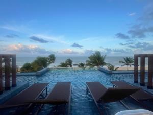 a swimming pool with chairs and the ocean in the background at Altamare - Pé na areia in Tambaú