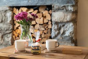 a table with a vase of flowers and two cups at Glasfryn Cottage Dolgellau in Dolgellau
