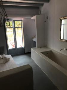 Theros Apartments Donoussa في دونوسا: حمام أبيض مع حوض استحمام ونافذة