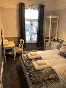 a bedroom with two beds and a desk and a window at Courtyard Holiday Apartments in Belper