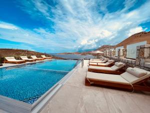 a resort pool with lounge chairs and the ocean at Vila D Boutique Hotel in Qeparo
