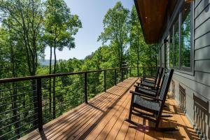 a deck with two chairs on the side of a house at Mountain to Sea Modern in Asheville