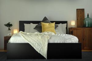 um quarto com uma cama preta e branca com almofadas amarelas em Cortina Apartment em Otari