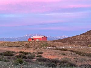 a red barn on a hill with mountains in the background at Yurt Escape with Amazing Country Views in Temecula