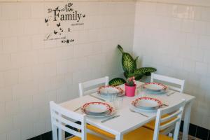 uma mesa branca com cadeiras brancas e pratos em casa mare incantevole em Alghero