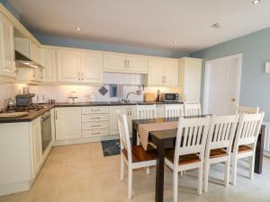 a kitchen with white cabinets and a table and chairs at Stillwaters in Bushmills