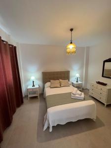 - une chambre avec un lit, deux tables et un lustre dans l'établissement Apartamento La Canela, à Nerja