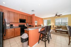 een keuken met oranje muren en een eiland met barkrukken bij Pool, Disney, Fast Wi-Fi - World Class 3-bed Home in Kissimmee