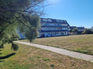 uma passagem num campo com um edifício ao fundo em Lion Beach em Lion-sur-Mer