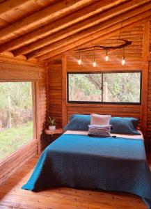 een slaapkamer met een blauw bed in een houten hut bij BRUMA BLANCA CHALETS in Medellín