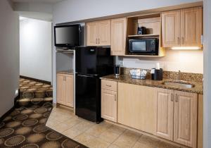 a kitchen with wooden cabinets and a black refrigerator at Best Western New Smyrna Beach Hotel & Suites in New Smyrna Beach