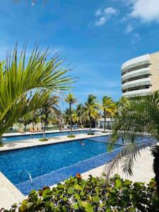 a swimming pool with palm trees and a building at Espectacular apto en Cartagena con salida directa a la playa in Cartagena de Indias