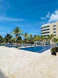 a swimming pool with palm trees and a building at Espectacular apto en Cartagena con salida directa a la playa in Cartagena de Indias