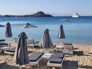 a group of chairs and umbrellas on a beach at Acrogiali Beach Hotel Mykonos in Platis Yialos Mykonos