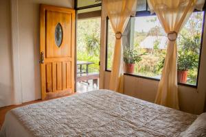 a bedroom with a bed and a door and windows at Cabinas las Manzanas Bed y Breakfast in El Copey