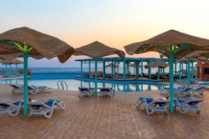 a swimming pool with umbrellas and lounge chairs and a pool at Radisson Blu Resort El Quseir in Quseir