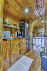 a kitchen with wooden cabinets and a stainless steel refrigerator at The Gemini-a dreamy, waterfront tiny cabin in Rogersville
