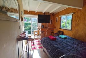 a bedroom with a bed and a flat screen tv at Kalas Cabañas in Puerto Varas