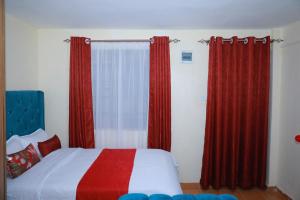 a bedroom with red curtains and a bed with a white and red blanket at Executive studio in Ruiru in Ruiru