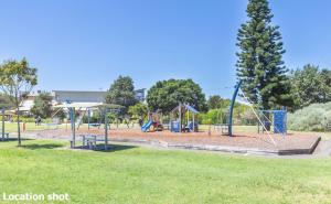 a playground with swings and a tree in a park at Fingal Court 2 2 Lentara St in Fingal Bay