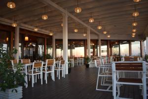 een restaurant met witte stoelen en tafels en ramen bij Posh villa 1 in Kavajë