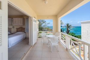 a bedroom with a bed and a balcony with a view of the ocean at Ocean Bliss Apartments in Christ Church