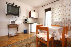 - un salon avec une table, des chaises et une télévision dans l'établissement Apartment Orebic 4546c, à Orebić