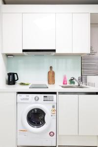 a washing machine in a kitchen with white cabinets at Sweet Stay in Seoul