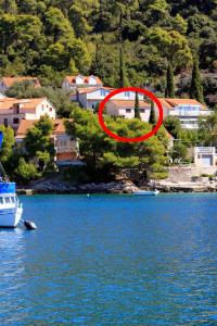 a red circle on top of a house next to a body of water at Apartments by the sea Brna, Korcula - 5902 in Smokvica
