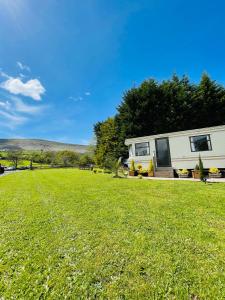 a large grassy yard with a caravan in the background at CAYORETREAT STATIC CARAVAN 