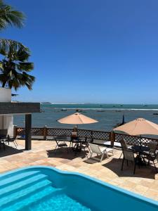 a swimming pool with chairs and umbrellas and the ocean at Pousada Ceu e Mar in Pipa