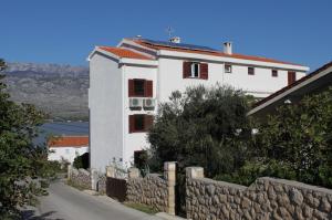 a white house with red windows and a stone fence at Apartments by the sea Vinjerac, Zadar - 5811 in Vinjerac