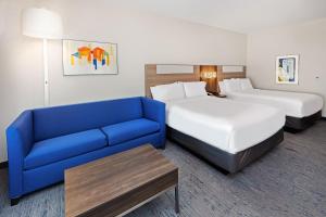 a hotel room with two beds and a blue couch at Holiday Inn Express & Suites - Houston SW - Rosenberg, an IHG Hotel in Rosenberg