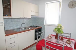 a kitchen with white cabinets and a table and a sink at Apartments by the sea Vinjerac, Zadar - 5824 in Vinjerac +31 photos
