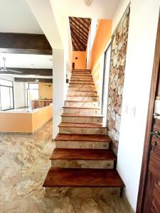 a staircase in a building with wood steps and a stone wall at VILLA LA MARQUESA in Puerto Escondido