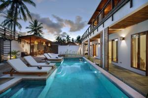 a pool with lounge chairs and a villa at Villa Sakura. Luxury 3 Bedroom Villa. in Selong Belanak