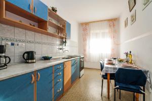 uma cozinha com armários azuis e uma mesa com cadeiras em Apartments for families with children Privlaka, Zadar - 5747 em Privlaka