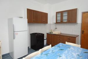 Il comprend une cuisine équipée d'une table et d'un réfrigérateur blanc. dans l'établissement Apartments by the sea Vrsi - Mulo, Zadar - 5790, à Vrsi