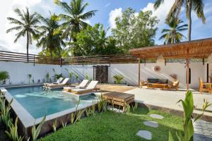 a backyard with a swimming pool and a house at Villa Sakura. Luxury 3 Bedroom Villa. in Selong Belanak