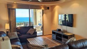 a living room with a couch and a flat screen tv at Luxury Condo Bella Sirena 405-C - Unmatched Views Over the Pool to the Sea in Puerto Peñasco