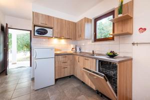 cocina con armarios de madera y nevera blanca en Apartments with a parking space Nin, Zadar - 5857, en Nin