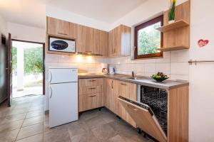 a kitchen with wooden cabinets and a white refrigerator at Apartments with a parking space Nin, Zadar - 5857 in Nin