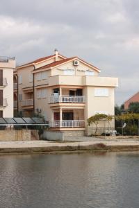 - un grand bâtiment à côté d'une étendue d'eau dans l'établissement Apartments by the sea Sukosan, Zadar - 5864, à Sukošan