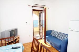 een woonkamer met een blauwe bank en een televisie bij Apartments by the sea Kozino, Zadar - 5803 in Kožino